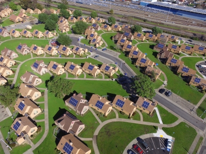 Aerial view of suburban neighborhood with solar panels on residential rooftops and green lawns