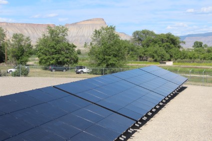 Ground-mounted solar panels in a rural landscape with mountains in the background