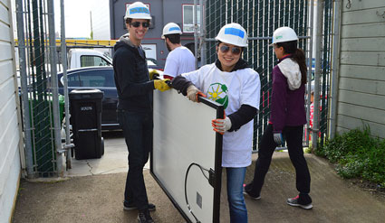 Two volunteers from the CPUC carry a solar panel.