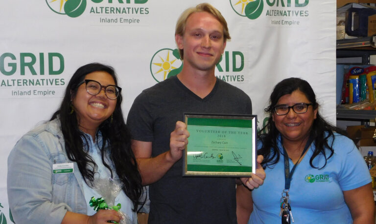 Man holding 2018 Volunteer of the Year award with two women at GRID Alternatives event
