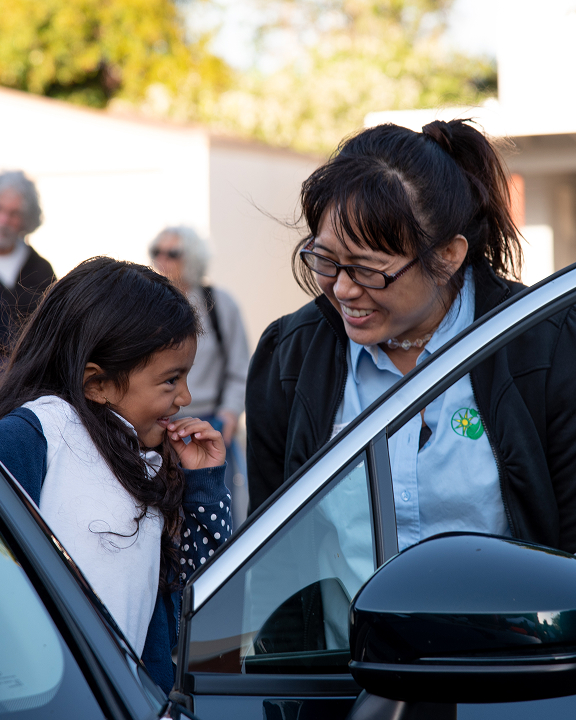 Adult and child smiling by car