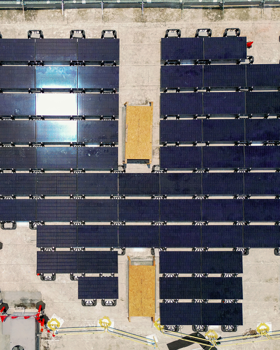Aerial view of solar panel arrays on a rooftop with yellow pathways between sections