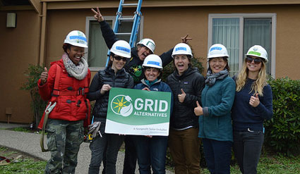 A group of women pose in front of a home where they just installed solar on the roof.