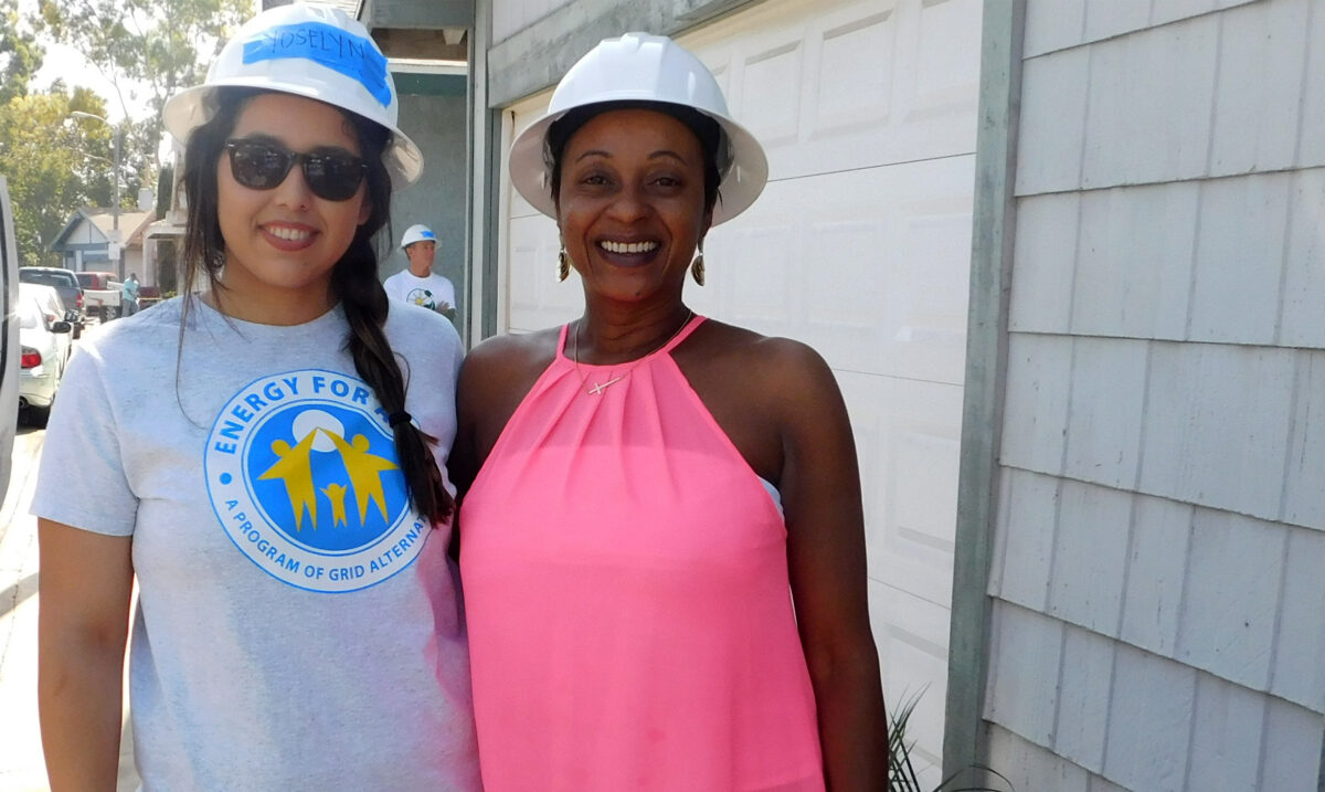 Two women wearing hard hats smile at the camera during an Energy for All program event