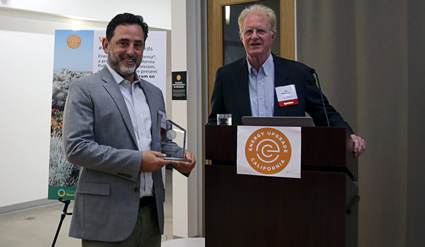 Two men at podium with Rotary logo; man on left holds award plaque