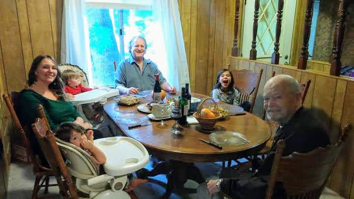 Family gathered around dining table for a meal together indoors