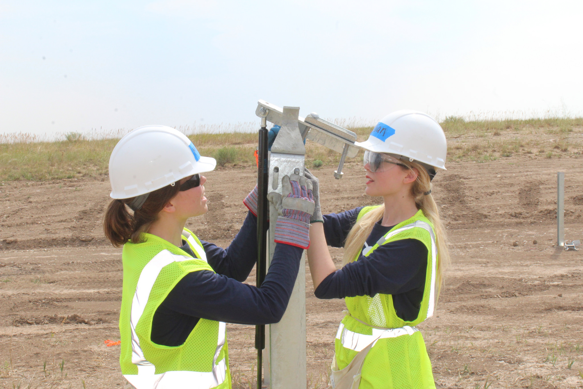 Gillian (right) works with a partner to place a dampener bracket on top of a large post.
