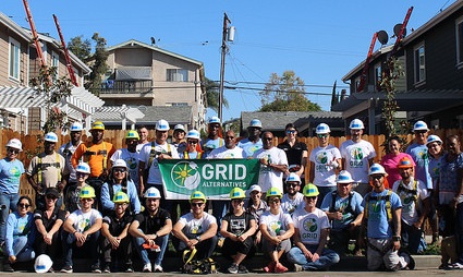 Large group photo of people wearing hard hats and GRID t-shirts gathered on a sunny residential street