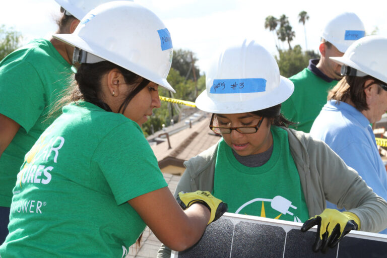 Two youths carry a solar panel