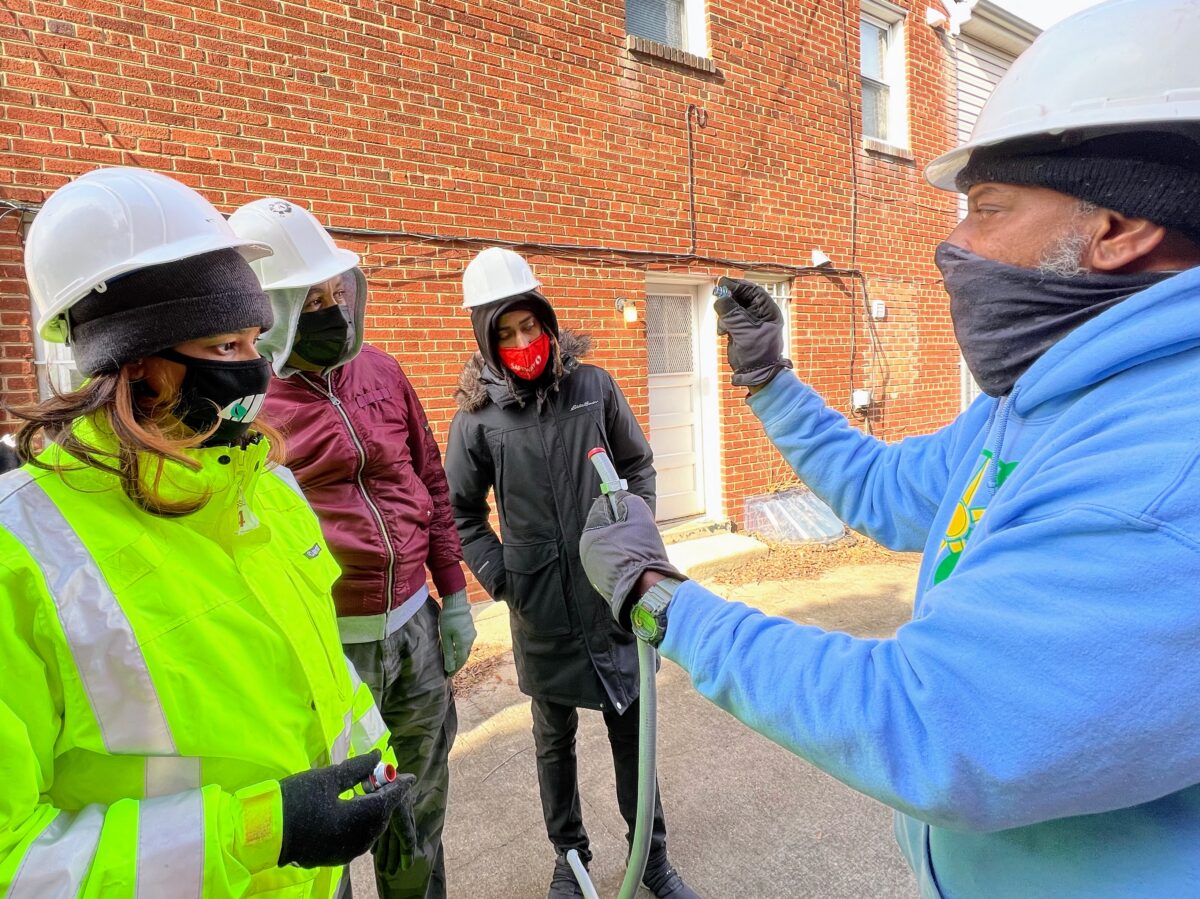 Solar Installation Supervisor Damon (right) shows Lillian (left) and other Solar Works DC trainees how to connect conduit.
