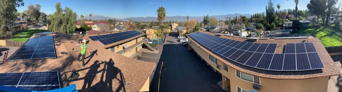 Aerial view of residential rooftops with solar panel installations in a suburban neighborhood