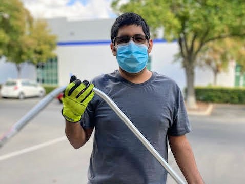 Worker wearing mask and safety gloves holding measuring tape outdoors