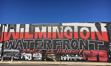 Wilmington Waterfront mural with red and black lettering on white building wall
