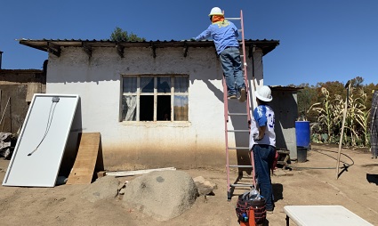 Worker on lift working on white building roof construction site