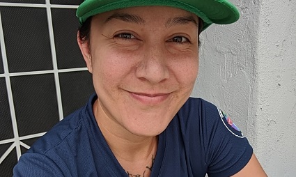Person wearing green cap and navy shirt smiling at camera outdoors