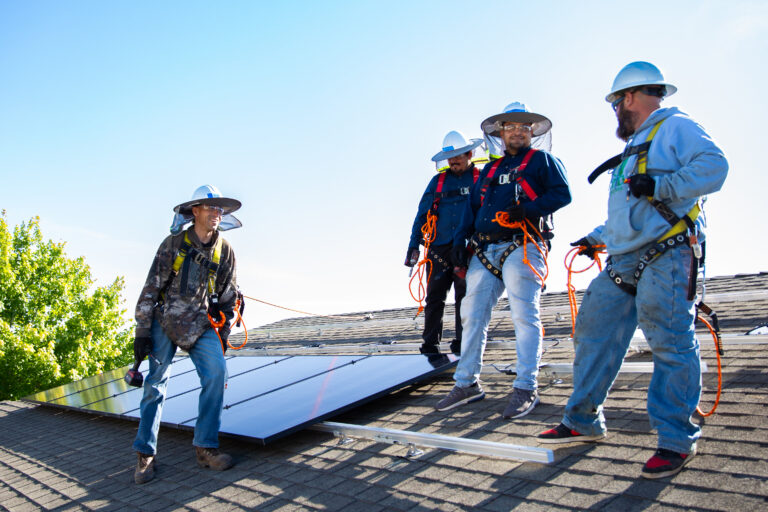 four men installing solar on a roof top