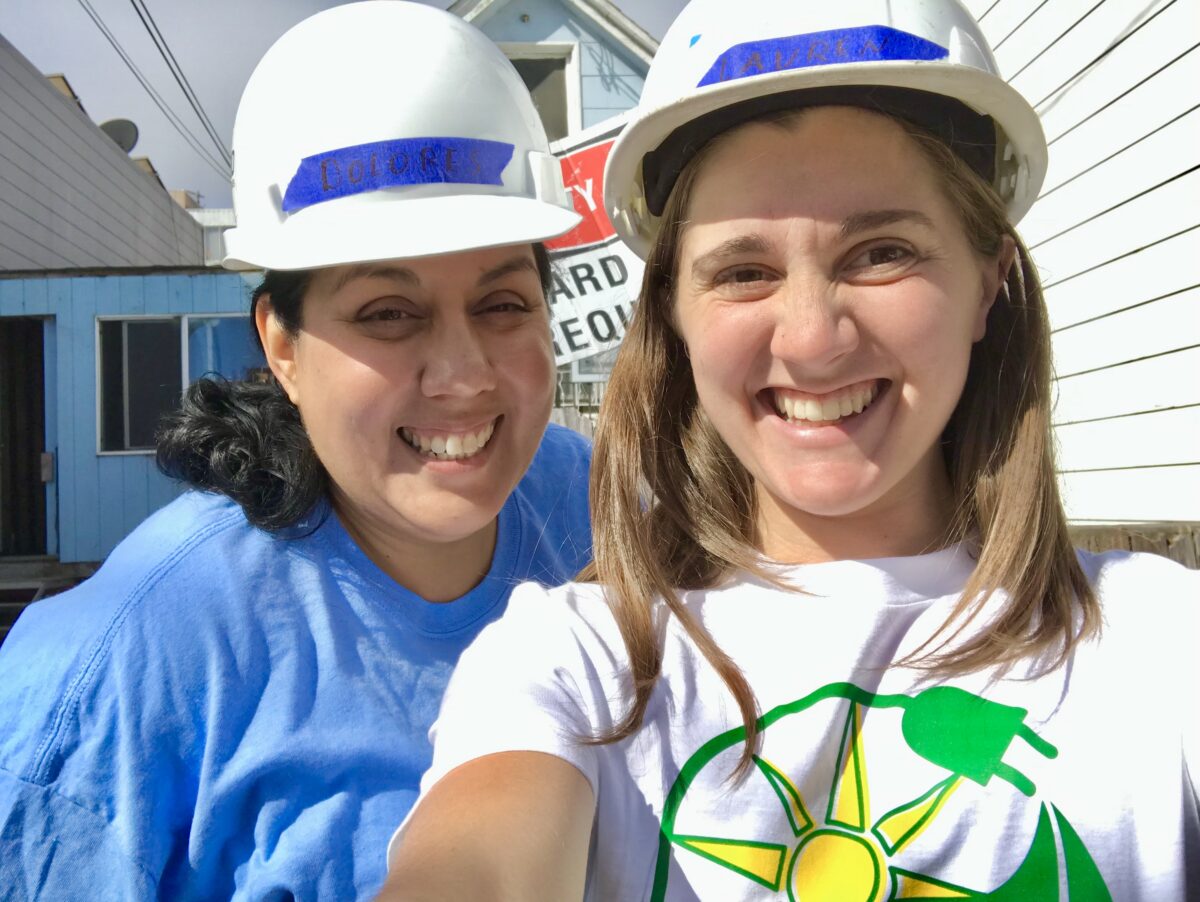 Dolores Garay and Lauren Morgan take a selfie while wearing hard hats at a GRID install