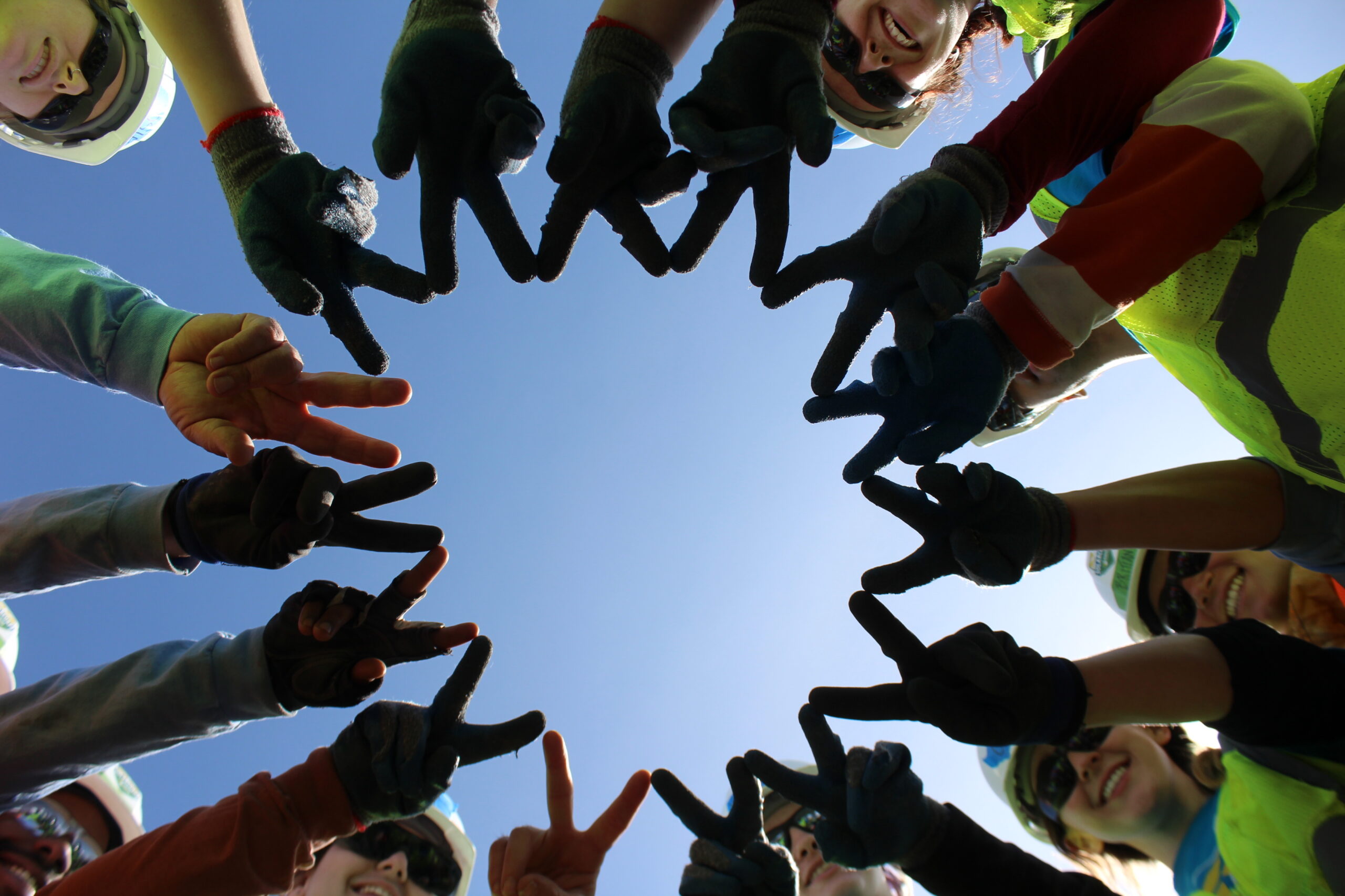 students hold their fingers out in peace signs in a circle
