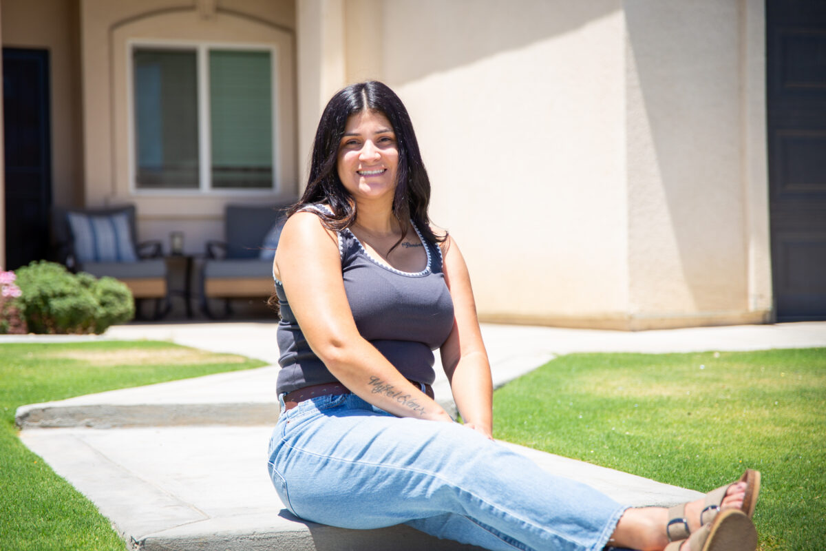 Woman sitting down in front of her home