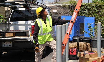 Worker in yellow safety vest installing metal bollard post from truck bed
