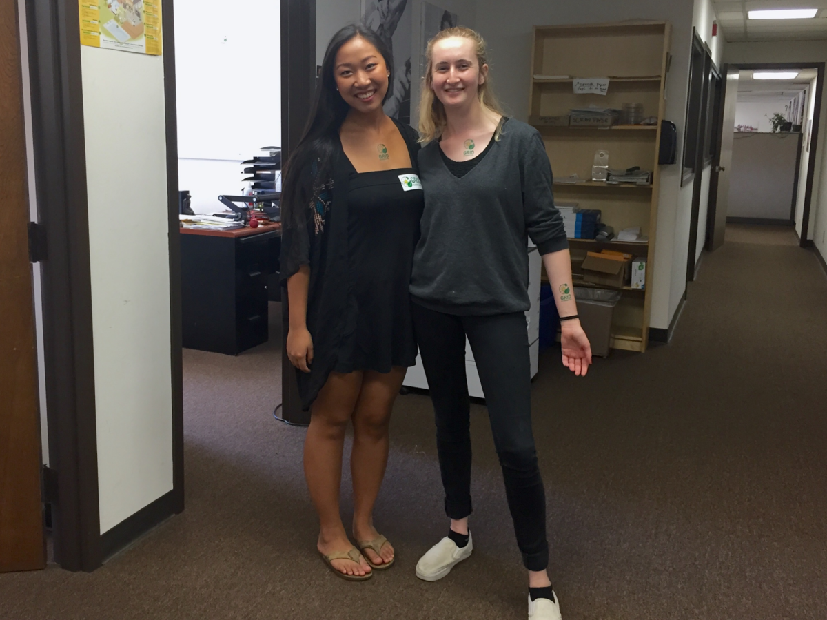 Two smiling women posing together in an office hallway