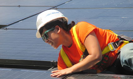 Worker in safety gear inspecting solar panels on roof