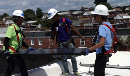 Homeowner Pamela and two volunteers put in a solar panel