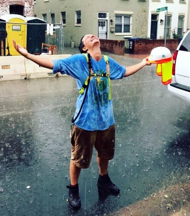 Kaly stands in solar gear, embracing a rain downpour