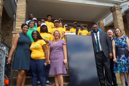 The group, including the Mayor, Nicole Steele, Solar Works DC job trainees, and Homeowner Amy gather