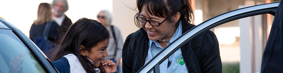 Woman smiles at child exiting an electric vehicle