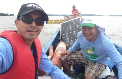 Two men in a boat displaying solar panel equipment during travel in Nicaragua