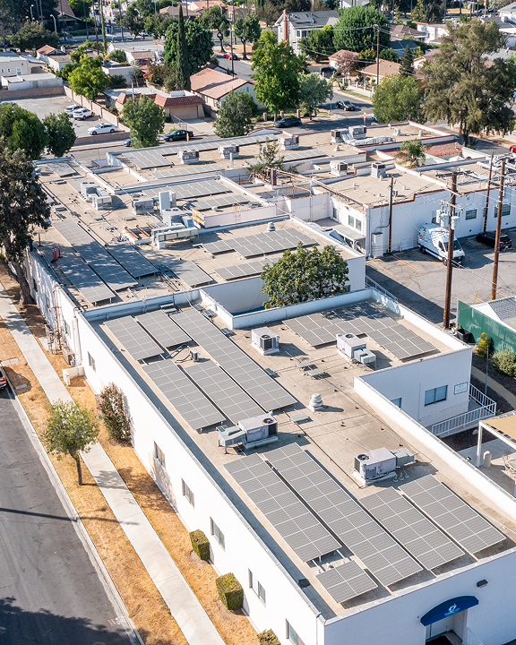 Aerial view of residential buildings with rooftop solar panels installed in a sunny neighborhood
