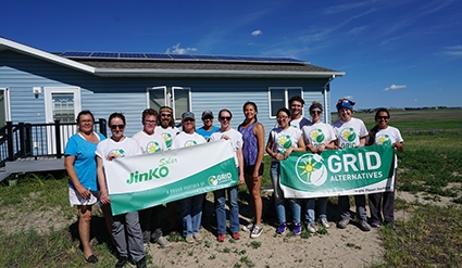 GRID staff, students from Cherry Creek High School, and home owners smile with banner in front of home with GRID and Ecological Action banners.