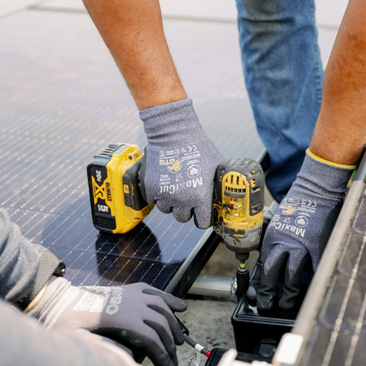 Workers installing solar panels wearing work gloves and safety gear