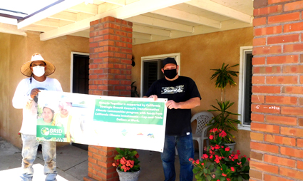 Two people holding a large green check for a charity donation indoors