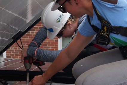 Under supervision of Nadine, a volunteer connects a solar panel to an inverter