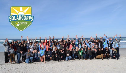 SolarCorps Grid team group photo on beach with logo and raised arms celebrating