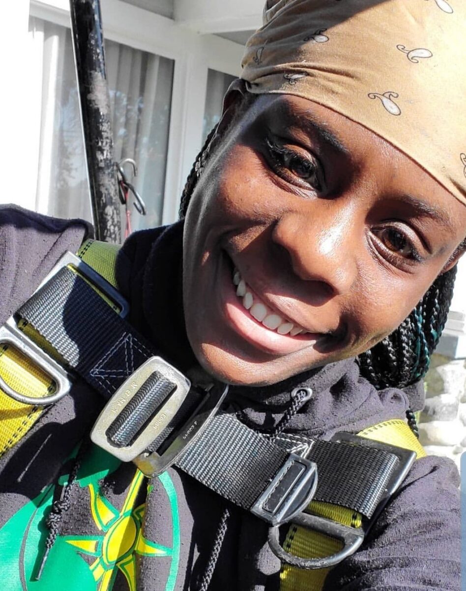 Person wearing black and yellow safety harness smiling at camera indoors