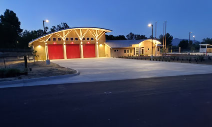 Soboba fire station exterior at dusk with illuminated yellow wooden roof and red garage doors