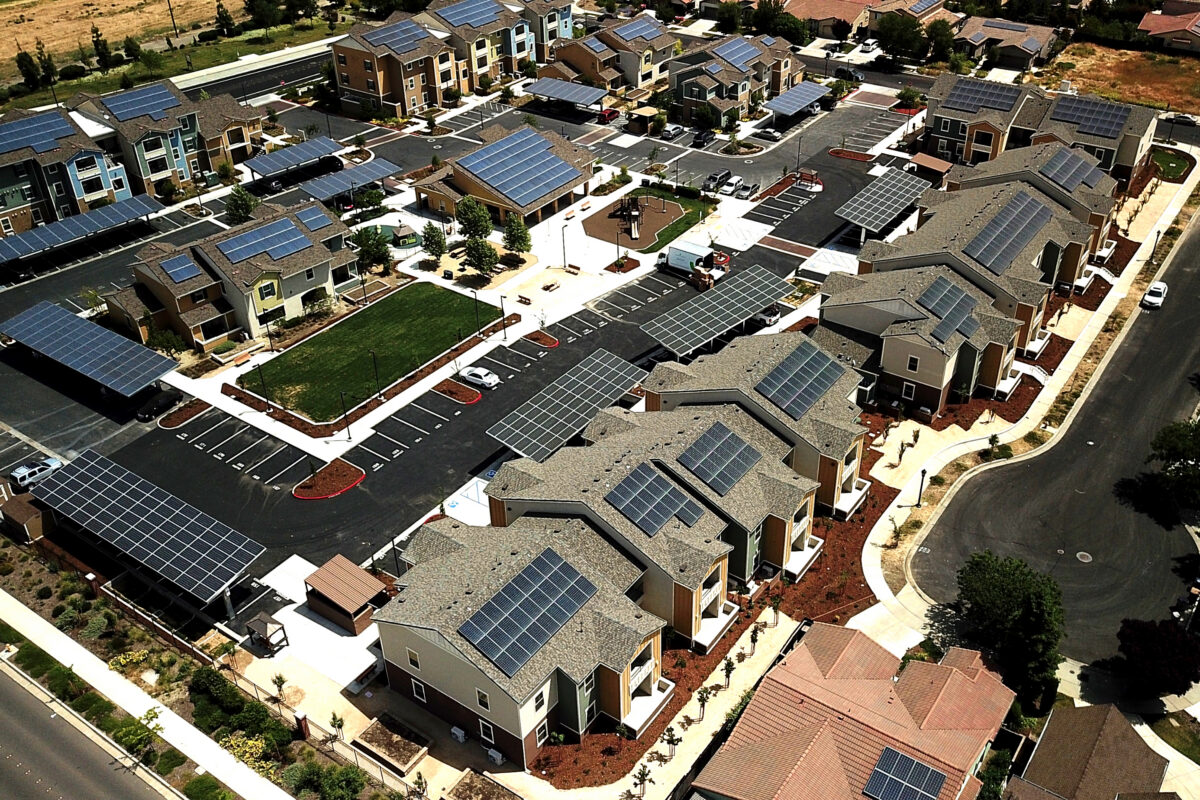 Aerial view of residential neighborhood with solar panels on most rooftops and parking areas