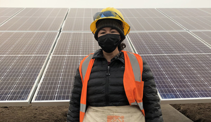 Worker in safety gear standing in front of solar panels