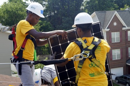 Two Solar Works DC job trainees carry a solar panel