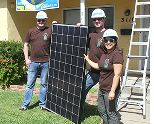 People hold solar panel in hardhats
