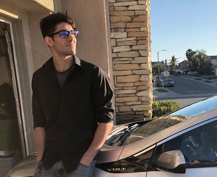 Vitto Riazzo leans against his 2016 Chevy Volt with the sun glowing on his face.