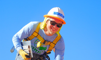 Smiling construction worker in safety gear and hard hat against blue sky