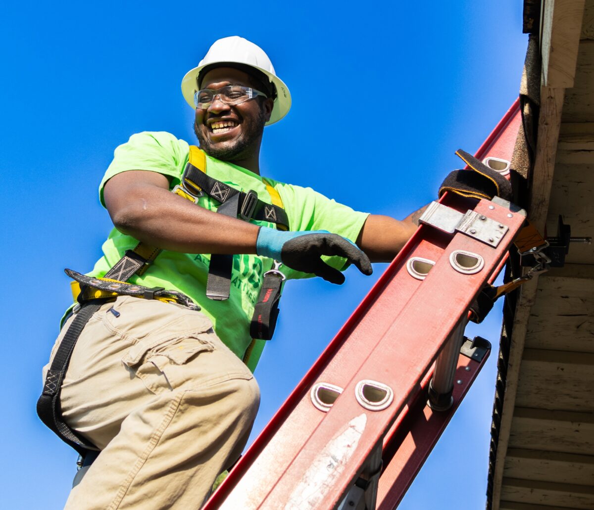 Darnell Asberry climbing ladder to work on the roof