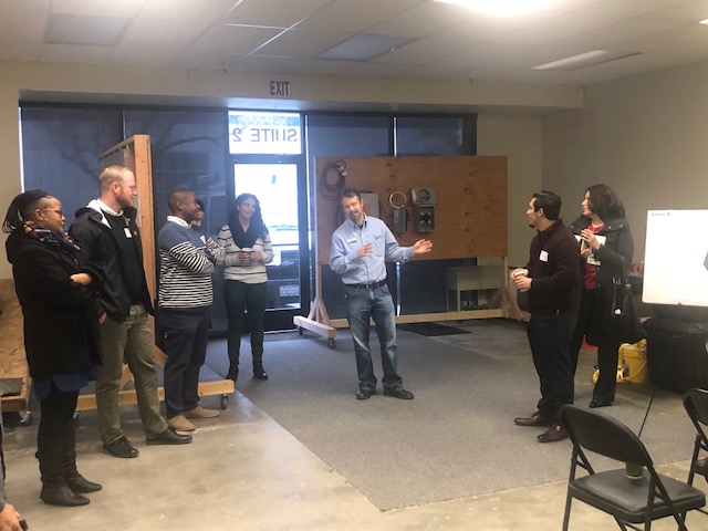 Group of people gathered in an indoor space during what appears to be a professional or community event presentation