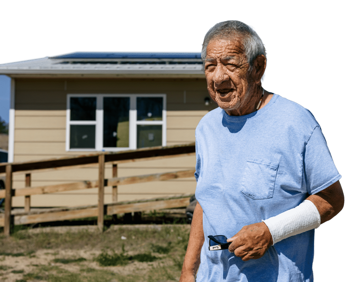 A homeowner stands outside his house, where a rooftop solar array catches the afternoon sun.