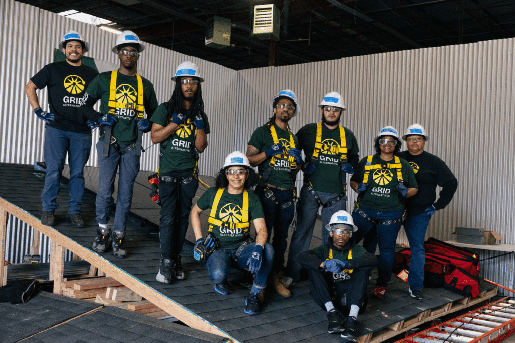A GRID crew in safety harnesses poses together on a rooftop under construction.