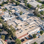 Aerial view of a large community building with solar panels covering its rooftop.